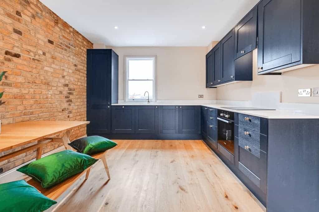 completed home extension dark cupboards with wood floor and brick wall