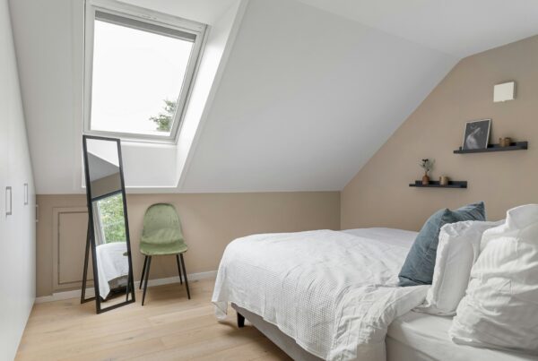 Modern loft conversion bedroom featuring a Velux-style roof window, sloping ceilings, fitted wardrobes and wooden flooring.